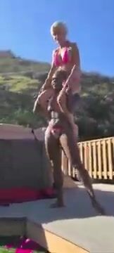 Thick strong black woman sensually lifts small blond bikini friend